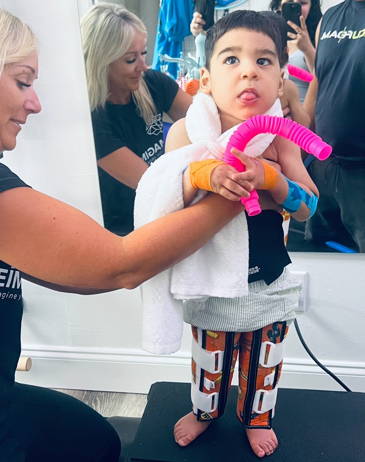 Jenny Mazurkiewicz supporting a toddler at standing midline during a therapy session